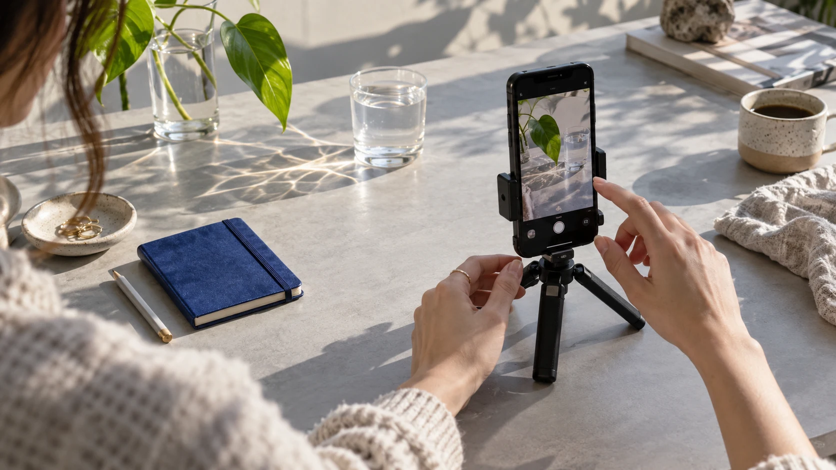A creator setting up a phone to film sunlight and glass on a table